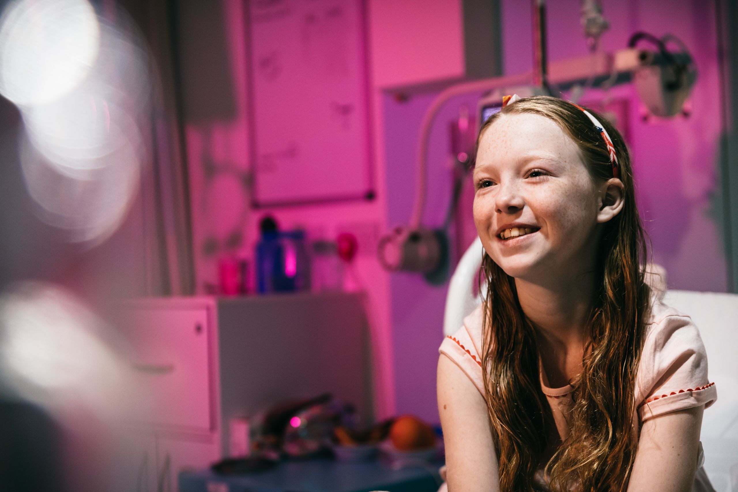 A happy looking young girl in a hospital bed.