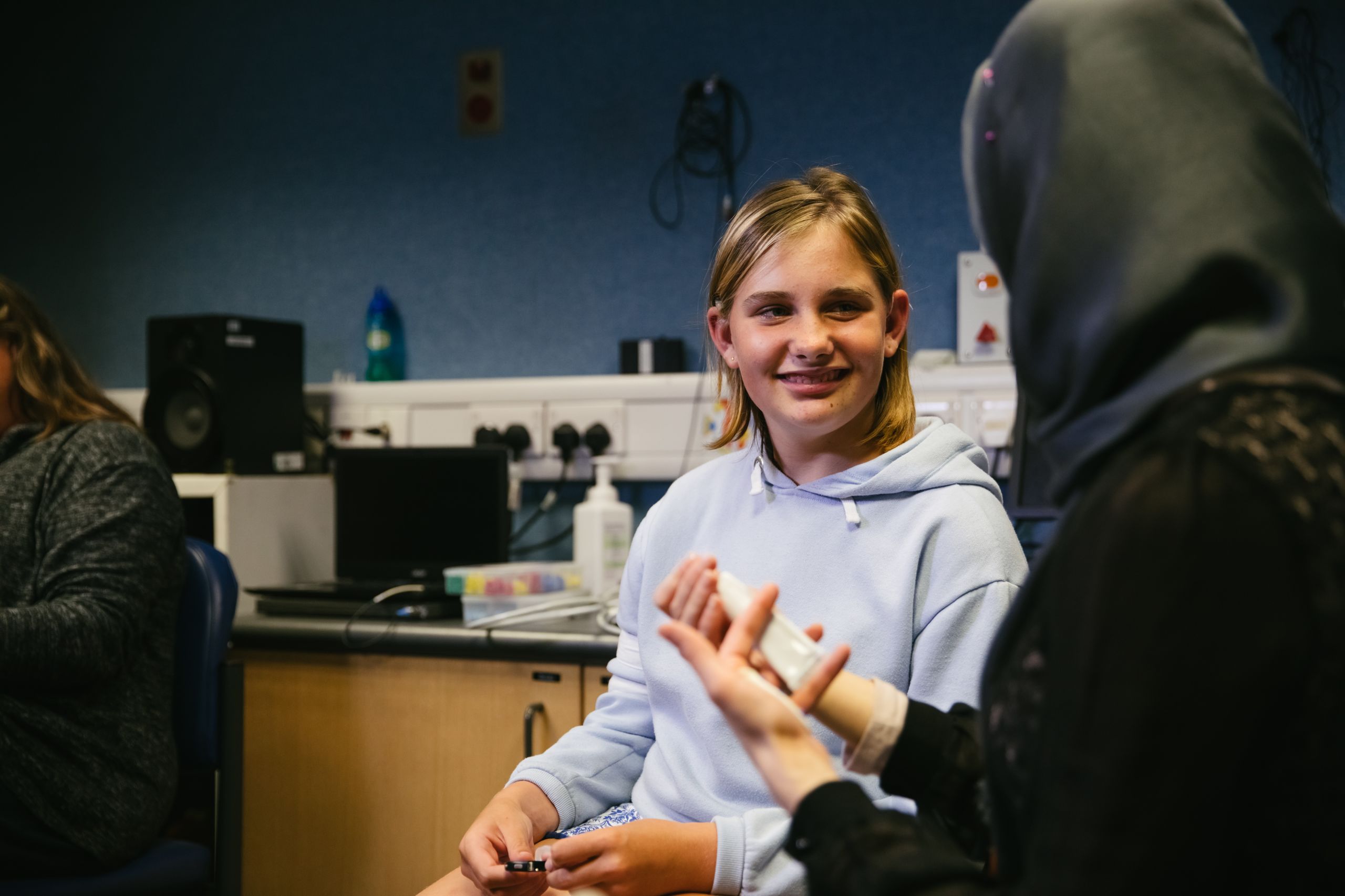 A smiling young girl talks to a doctor wearing a hijab.